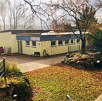 Ein gelbes Gebäude mit einem Steingarten und Herbstblättern.