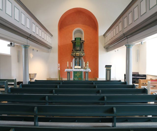 Das Innere einer Kirche mit Holz-Kirchenbänken.