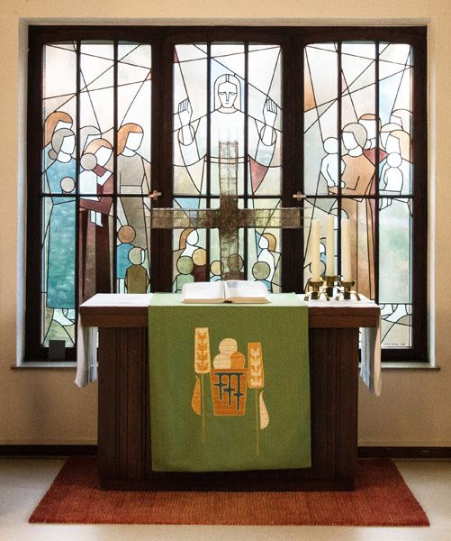Ein Altar vor einem Buntglasfenster.