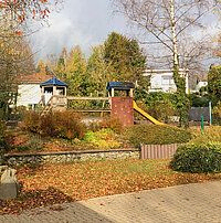 Ein Spielplatz mit einer Holzkonstruktion und Rutsche im Herbst.